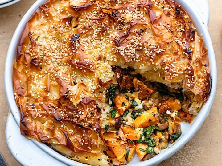 Vegetarian pie with pumpkin and a golden crust in a white dish.