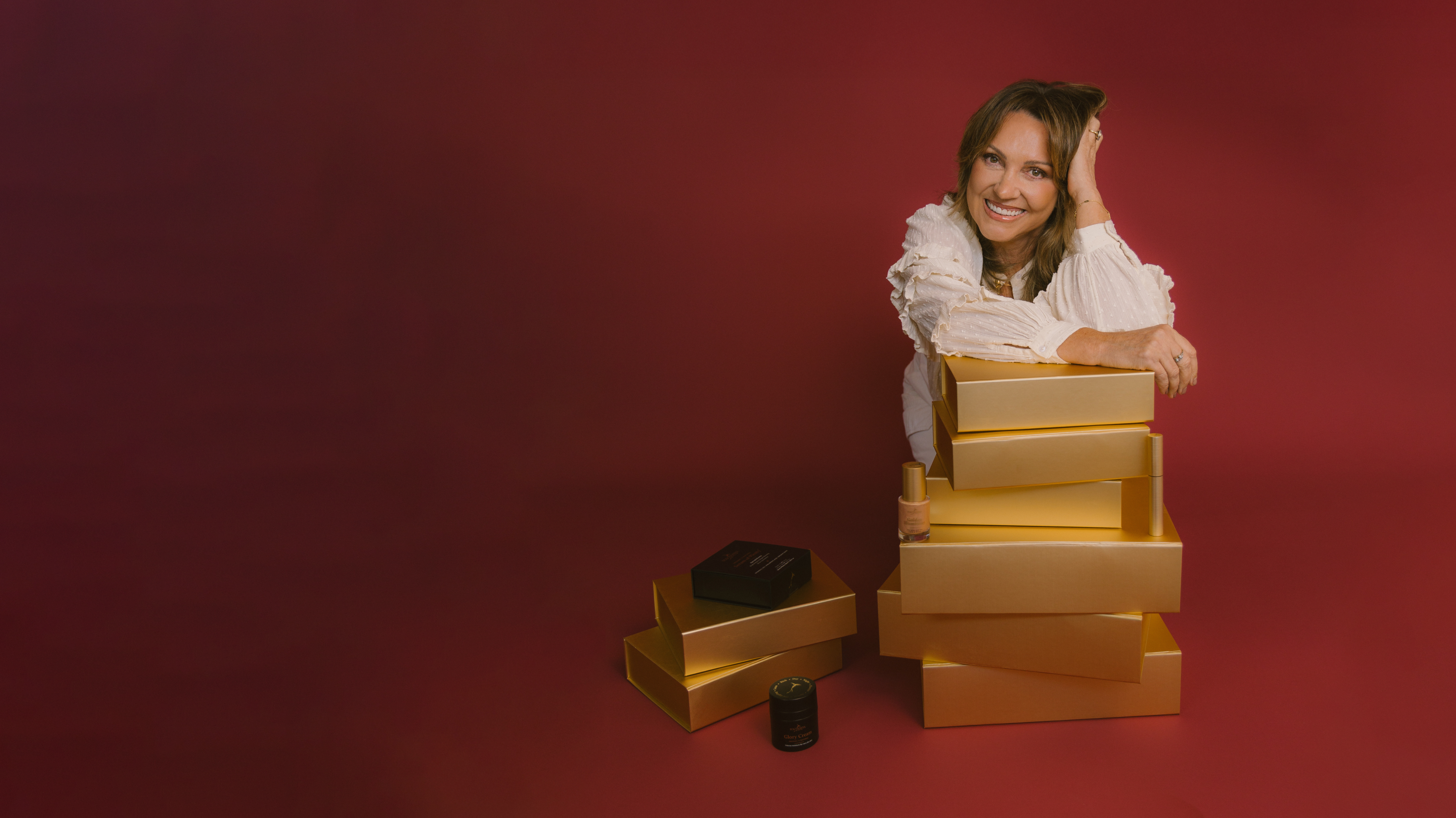 Sonya sitting on a stack of gold boxes against a red background