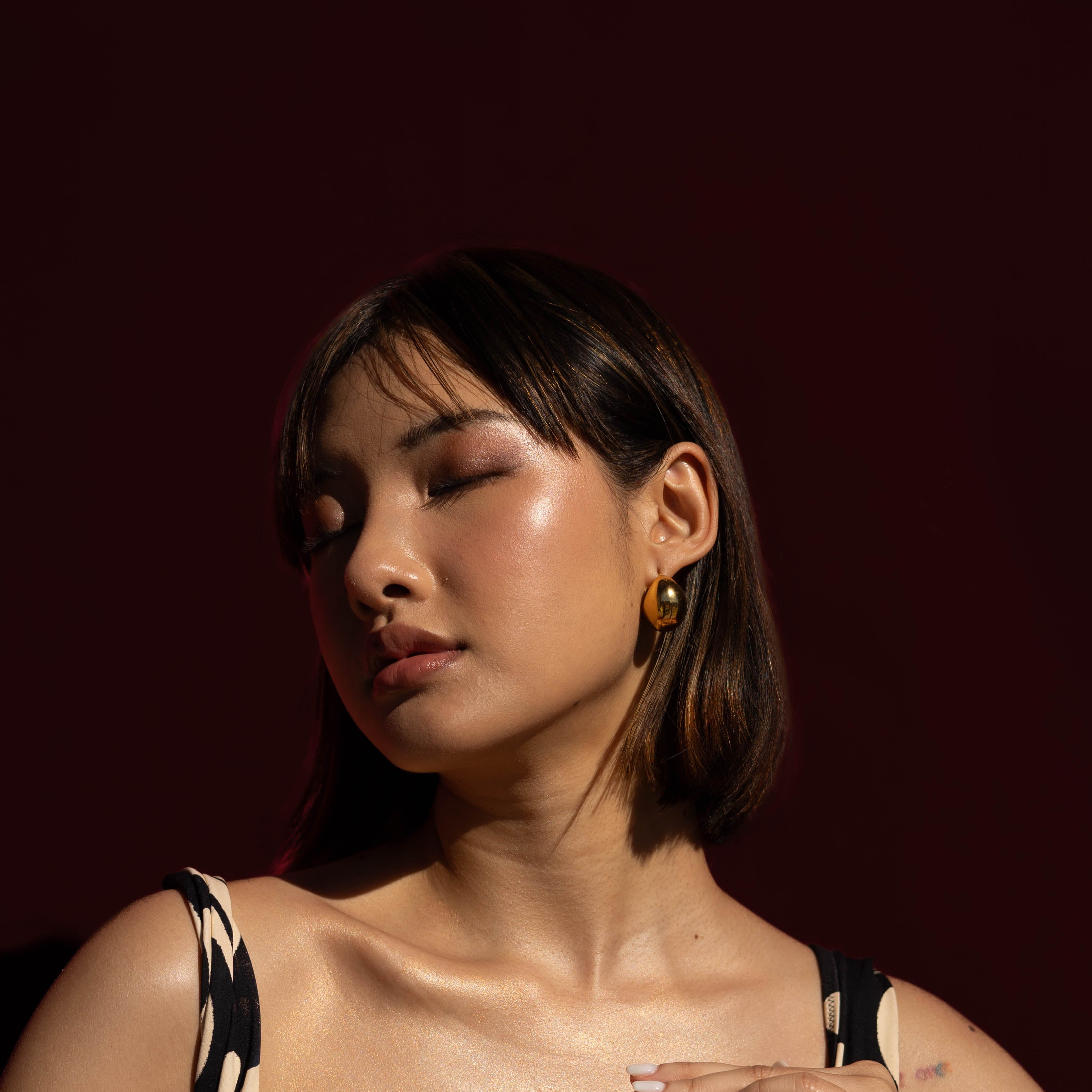 Woman holding Golden Illuminiser showing the shimmering effect on her skin