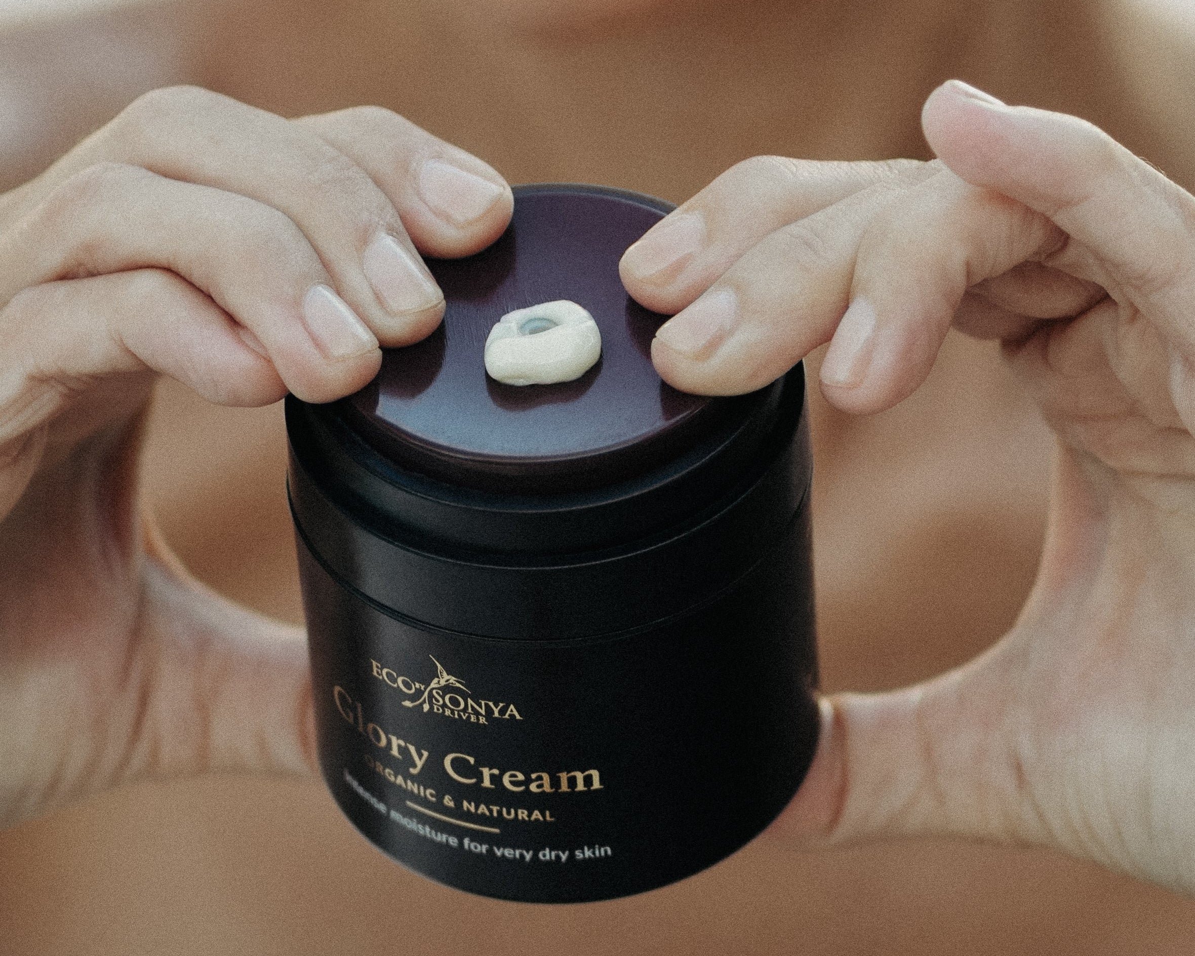 Person squeezing Glory Cream out the jar showing creamy texture 