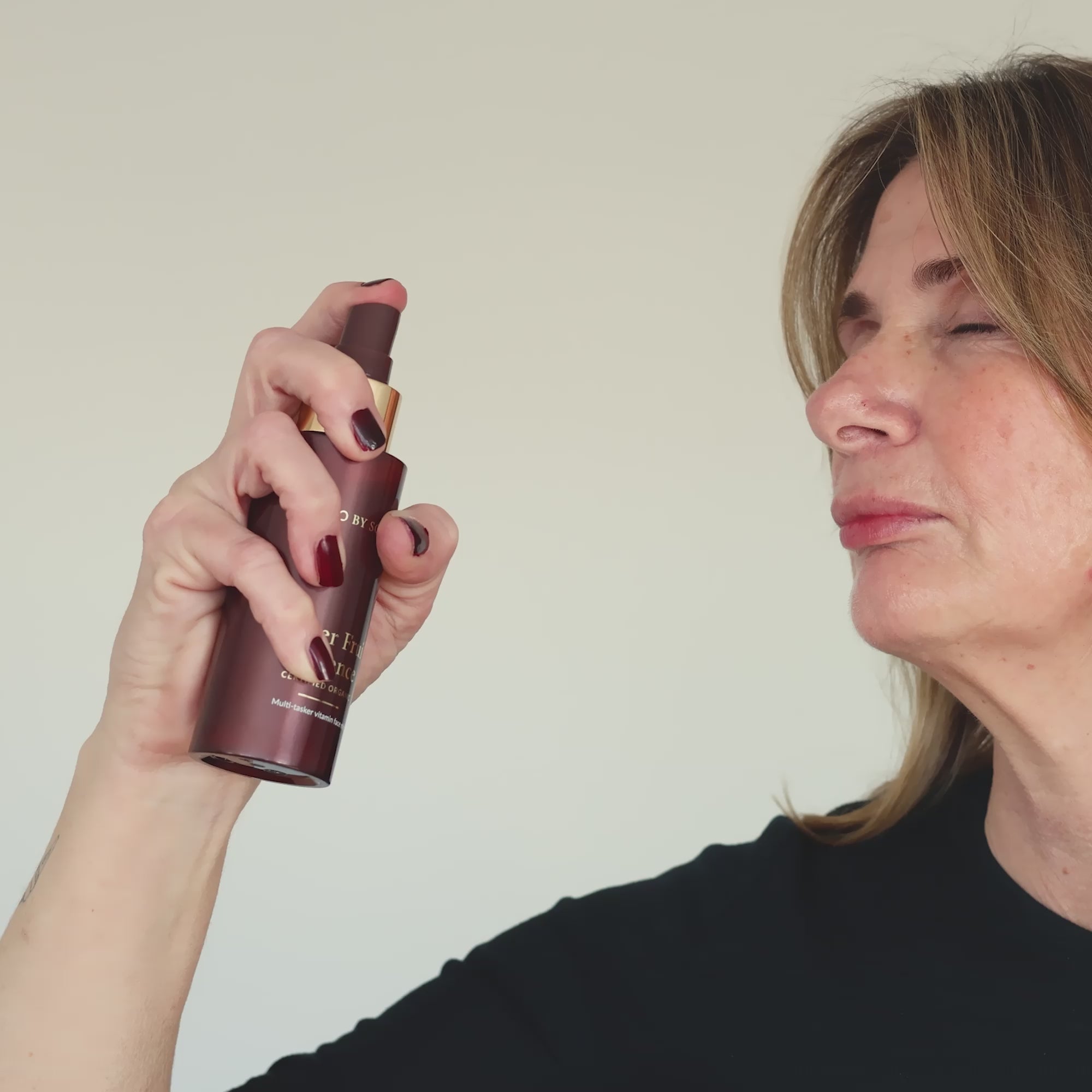 Woman spraying Eco By Sonya Super Fruit Essence onto her face